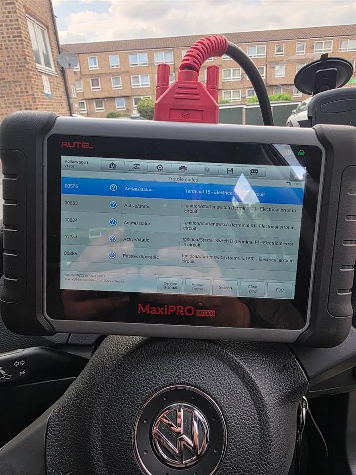 Autel MaxiPRO scanner on a VW Golf steering wheel, listing ignition switch fault codes